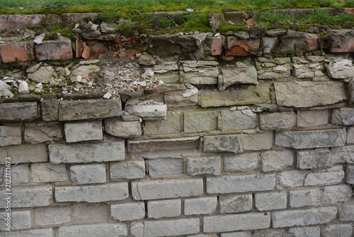 A light gray wall, an old building, a fence with green moss and moisture. Light gray, red bricks, beautiful, stylish brickwork.