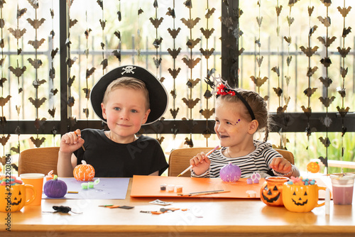 Two children painting Halloween pumpkins during festive arts and crafts activity