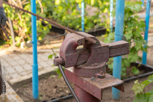 Fotografía Closeup of weathered red pipe bender clamping steel rod outdoors