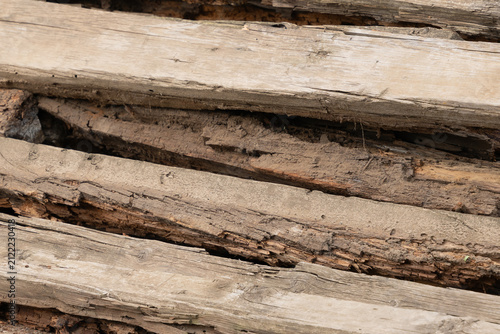 Fotografie Closeup of aged wooden planks showing cracked surfaces, peeling layers, embedded soil
