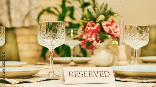 Reserved table in a restaurant with glasses and a red flower