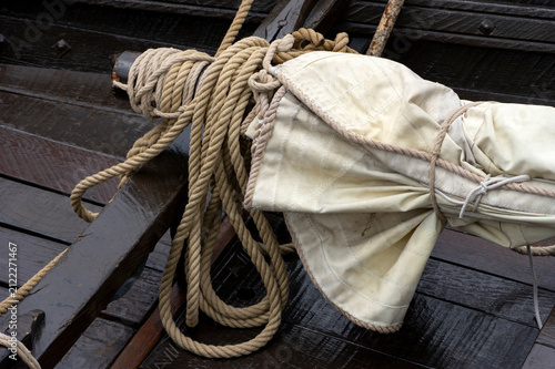 Konstfotografi Coiled sailing rope on folded canvas sail aboard traditional wooden sailing boat