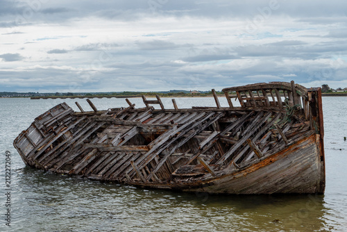 Canvas Print Decaying wooden hull submerged partially in murky lake or river