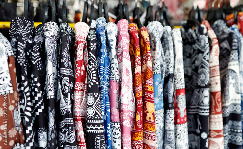 Colorful elephant patterned fabrics hanging in row, showcasing Asian textile design, Hawaii shirt, cultural fashion, Thai traditional patterns, and vibrant clothing industry background