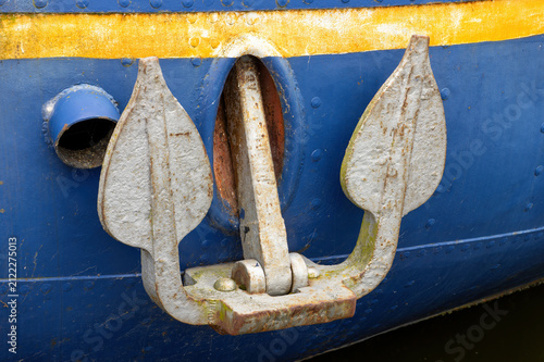Traditional ship anchor secured to the bow of a historic wooden vessel