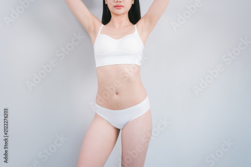 Foto Young woman in white underwear posing against a plain light background, cropped