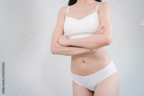 Фотография Cropped view of a woman in white underwear standing against a plain light backgr