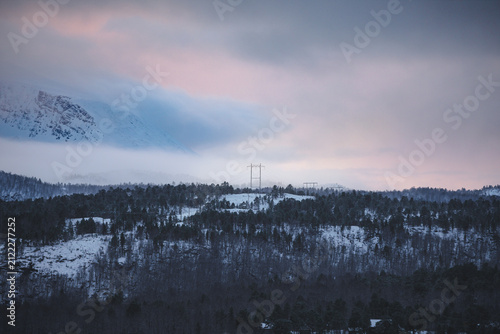 Winter view of power lines crossing snowy forest near Malangen Fjord in Troms, Northern Norway
