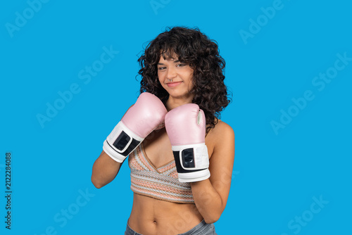 Young woman boxing with pink gloves, showing strength