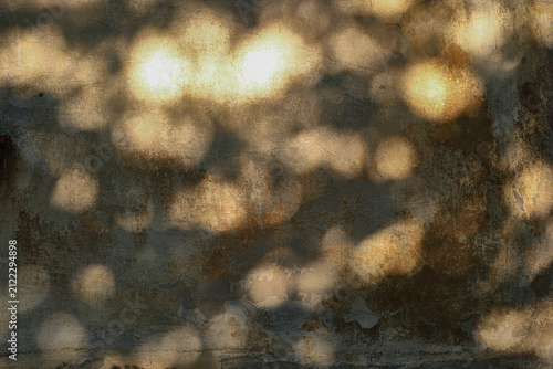 Weathered concrete wall texture with warm glowing light spots, distressed details and earthy tones, creating an atmospheric vintage industrial background