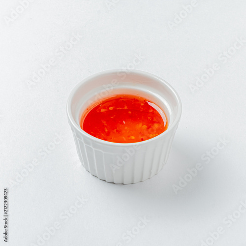 Obraz na plátne Bright and spicy chili sauce in a small white ramekin on a clean surface
