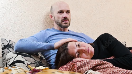 Caring Husband Comforting Sad and Depressed Wife Lying on Sofa at Home