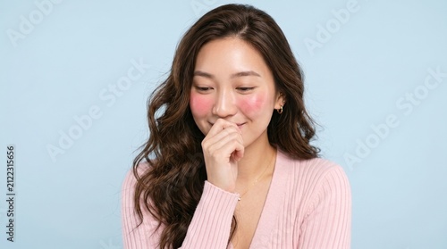 Young woman blushing with a bashful gesture. Shy girl smiling with hand over her mouth.