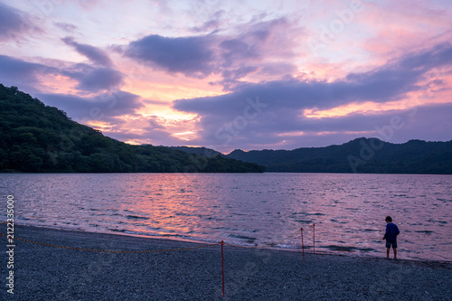 фотографія 夕暮れの湖畔で幻想的な空を眺める子どもの後ろ姿