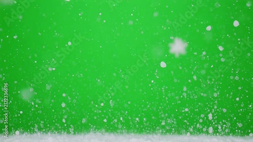 Snowfall particles gently falling against a vibrant green screen background with subtle light flares