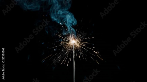 Sparkler igniting and burning with smoke trails against a dark background in cinematic motion