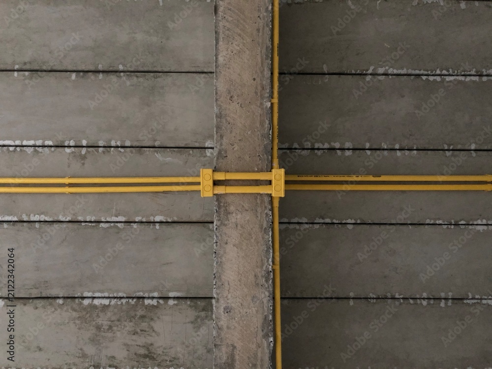 Fototapeta premium Yellow pipe pattern on concrete wall