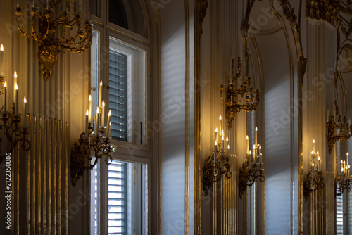 Interno monumentale barocco con applique dorate storiche e candele accese riflesse negli specchi della galleria di un palazzo imperiale