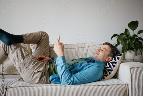 Man Lying on Sofa Using Smartphone for Online Dating Apps