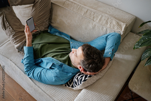 Man Lying on Sofa Using Smartphone for Online Dating Apps