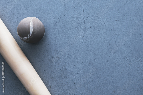Black baseball and wooden bat on blue textured surface with generous copy spa...