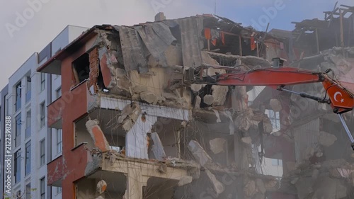 Demolition of building, excavator with hydraulic crusher is tearing down the old typical Turkish multi-storey apartment, residential building in Istanbul, Turkey: slow motion