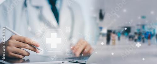 Foto Professional physician taps digital medical cross interface using stylus, accessing online healthcare assistance, hospital clinic services, and emergency patient treatment records in blurred office