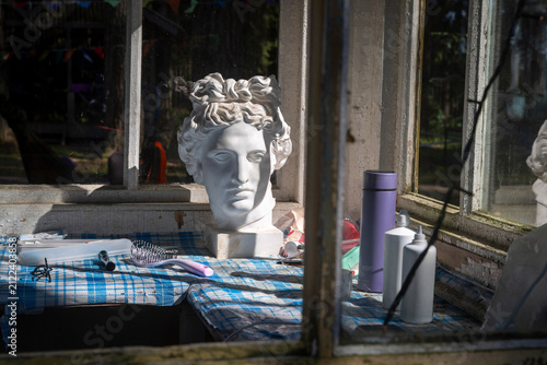 Plaster head sculpture on windowsill among toiletries