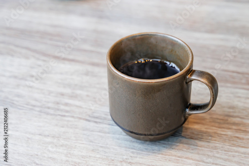 木目テーブルの上に置かれたマグカップ入りのホットコーヒー俯瞰