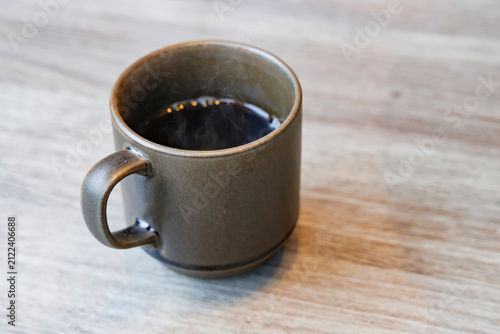 木目テーブルの上に置かれたマグカップ入りのホットコーヒー俯瞰