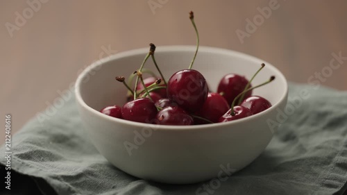 Slow motion man hand picking fresh cherries from white bowl