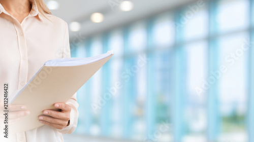 Document management, Business administration. Office employee holds a folder with paper documents, supporting records management, document review, compliance and corporate administration.