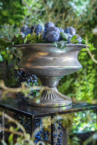 Fresh ripe plums in an antique silver bowl at a catering event