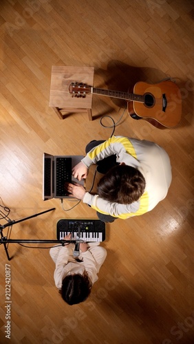 Konstfotografi Two people collaborating on music production, one person typing on a laptop and