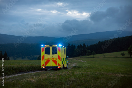 Emergency medical service ambulance vehicle driving on mountain road during twilight. Remote area rescue mission, urgent healthcare response and medical transport concept.