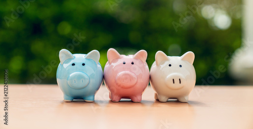 Three piggy banks on table with green nature background, Save money for prepare retirement concept.