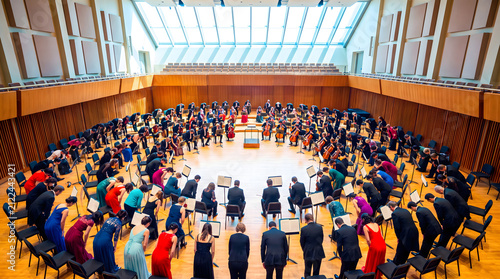 Symphony orchestra members bowing collectively in a rehearsal hall after performance