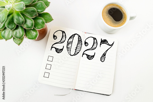 New year resolutions 2027 on white desk. 2027 resolutions list with notebook, coffee cup on table. Goals, resolutions, plan, action, checklist concept. New Year 2027 template, copy space