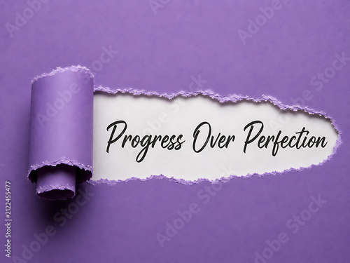 Progress over perfection message revealed through torn purple paper on a lilac background