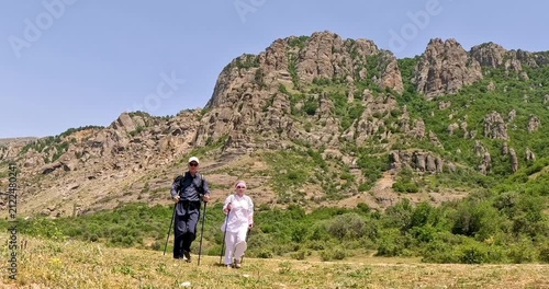 Couple of happy tourists with backpacks walk to the top of the mountain.