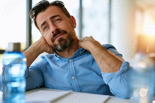 Office worker loosening collar at modern desk during summer heat