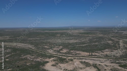 Aerial view of vast dry arid plains and shrubland under a blue sky.