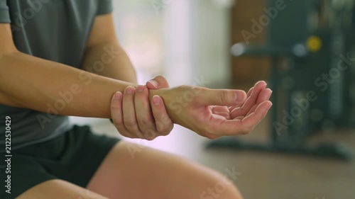 Woman holding sore wrist after exercise at gym.