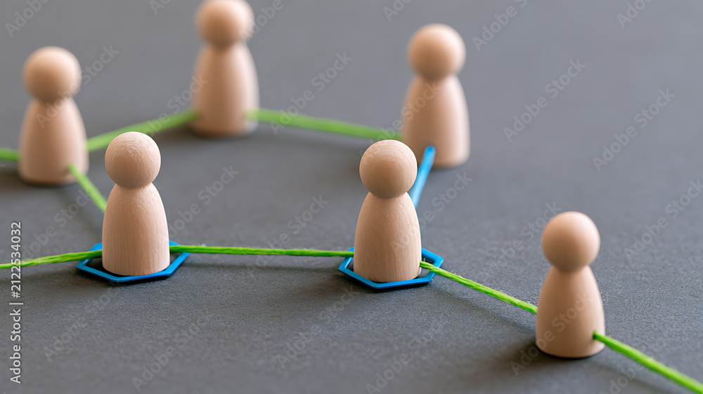 Obraz premium Wooden figures connected by green thread illustrate concepts of network, team, social bond, or communication on a gray background