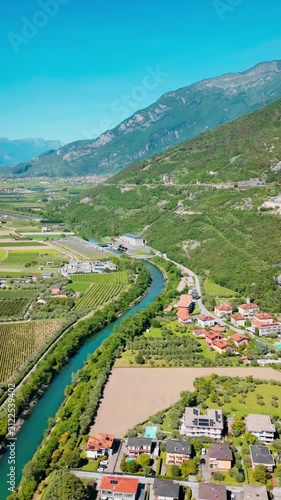 Mountain valley landscape near Lake Garda with river and farmland. Green fields, rural settlement and alpine terrain in northern Italy
