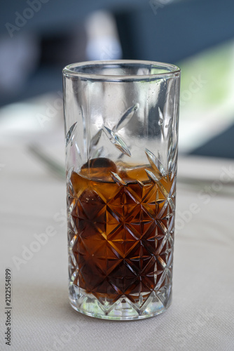 Obraz na plátně A patterned crystal glass filled with a dark beverage and ice sits on a light-colored table surface
