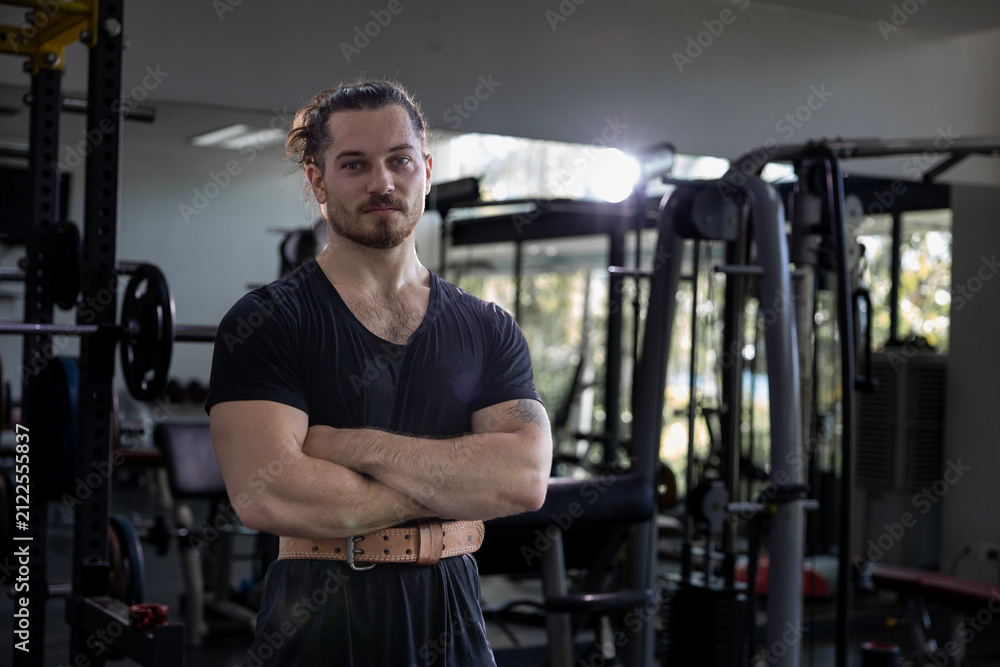 Fototapeta premium Portrait of caucasian muscular man with perfect abs and bicep muscle inside gym with dark background for exercise and workout in high contrast low key lighting studio