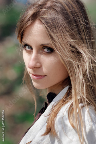 Fotografie Close-up outdoor portrait of a blonde woman looking over her shoulder with windblown hair and blue eyes