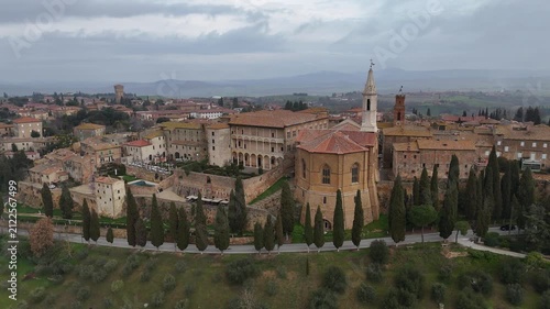 Drone horizontal panning shot moving right to left behind the historic Pienza Cathedral architecture
