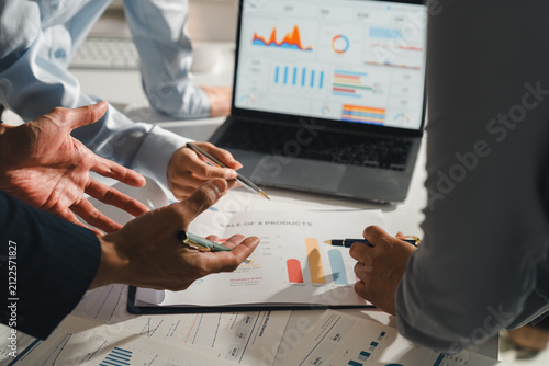 Business team analyzing financial data and charts on laptop during office meeting